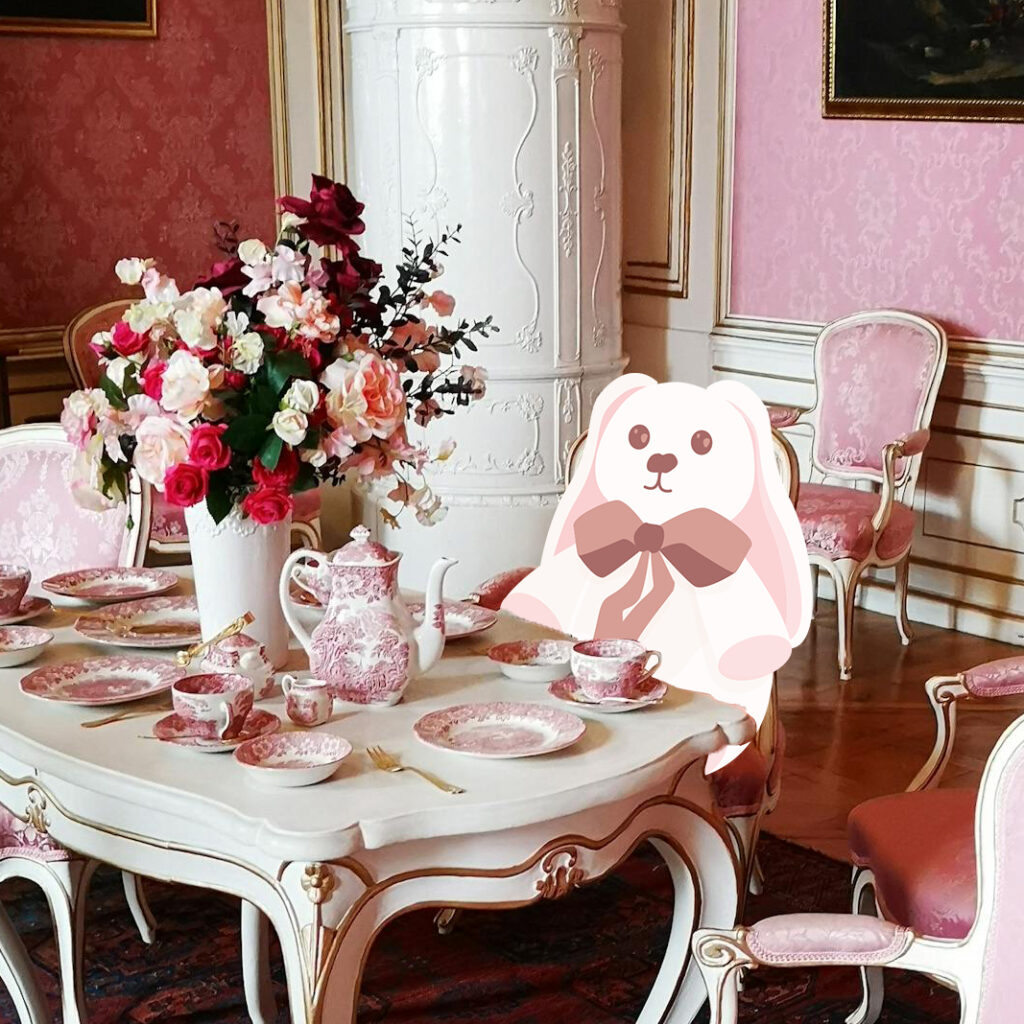cartoon rabbit sitting at a table set with flowers and a tea set.